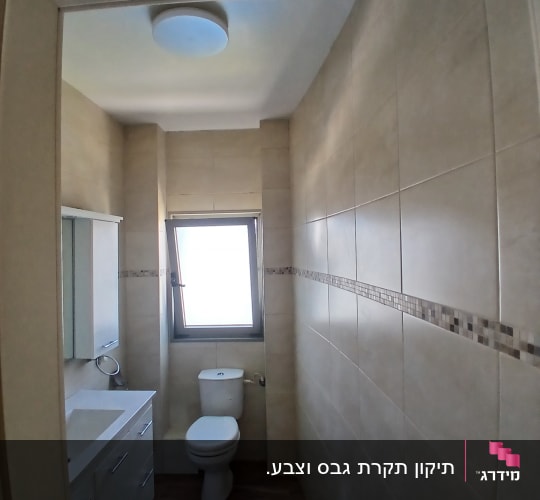 חדר אמבטיה עם אריחים בהירים ושירותים